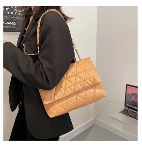 Gros plan sur un sac bandoulière camel en simili cuir matelassé avec chaîne dorée