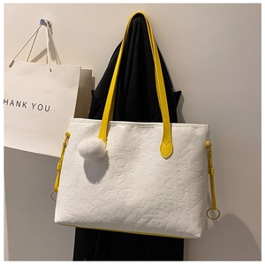 Detail of white PU leather tote with yellow handles and embossed cartoon dog patterns
