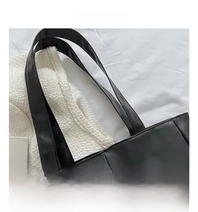Detailed close-up of reinforced black faux leather straps on a modern quilted tote bag