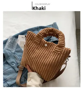 Detailed shot of a khaki corduroy tote bag with woven handles on a denim jacket