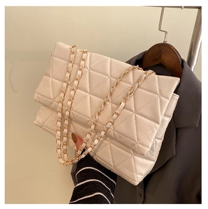 Détail du sac à bandoulière matelassé beige avec coutures géométriques et chaîne