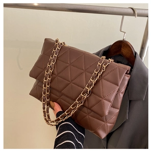 Détail d'un sac à main matelassé marron foncé avec une élégante chaîne dorée