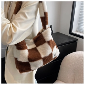 Close-up of brown and white checkered plush faux fur shoulder bag with metal logo detail