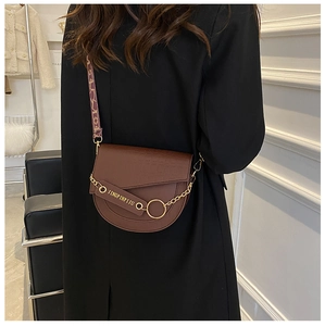 Braune Satteltasche getragen mit Blumen-Schultergurt und goldener Kette