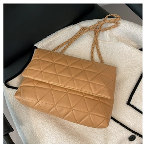 Détail macro de la texture matelassée et de la chaîne dorée sur le sac à bandoulière