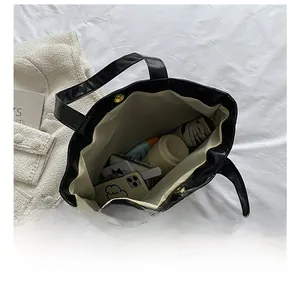 Interior view of black tote bag showing large capacity with beige lining and magnetic snap