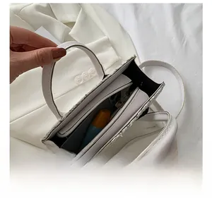 Dettaglio degli scomparti interni di una piccola borsa in tweed bianco con oggetti quotidiani