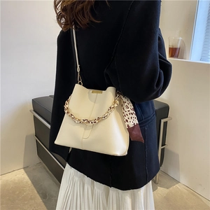 Sac seau beige chic avec ferrures et détail de foulard léopard sur la poignée