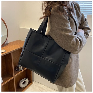 Large black woven leather tote bag shown on model with shoulder strap for work