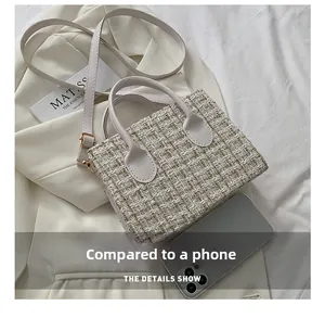 Dettaglio della borsa a tracolla in tweed accanto a uno smartphone per le dimensioni