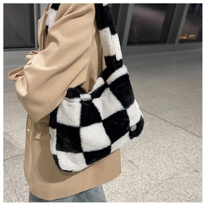 Black and white checkerboard plush shoulder bag shown on a model in a beige blazer