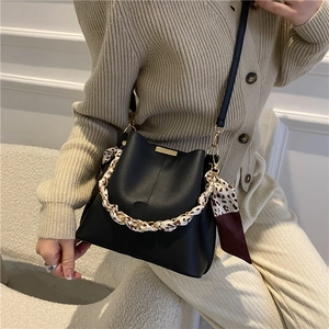 Sac seau noir chic avec foulard en soie léopard sur la poignée chaîne porté par modèle