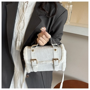 Detail der weißen Plüsch-Schultertasche mit Lederriemen und Goldschnallen am Modell