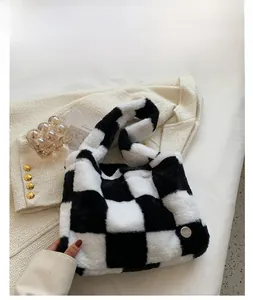 Detail of soft black and white checkerboard plush handbag with silver metal ornament