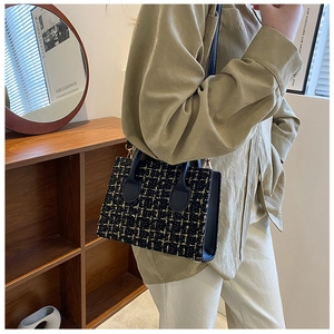 Modelo con bolso bandolera de tweed negro y dorado con elegante patrón de cuadros