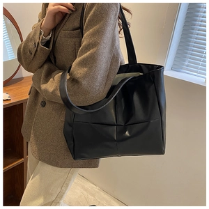 Detailed view of black quilted PU leather tote bag with wide shoulder strap