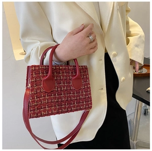 Detalle del bolso de tweed rojo con textura tejida y asa de cuero liso para mujer