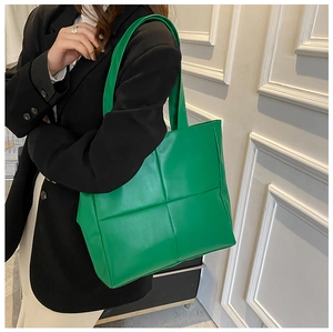 Detail of green oversized quilted tote bag in synthetic leather worn by model