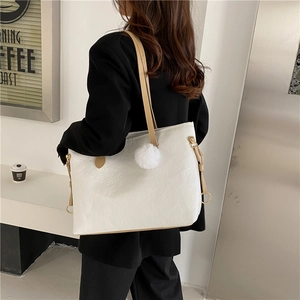Large white tote bag with embossed pattern and plush charm shown on female model