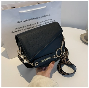 Details der schwarzen Satteltasche mit Krokostruktur, Metallkette und breitem Gurt