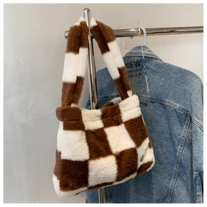 Detail of checkered plush shoulder bag in brown and white hanging on a hanger