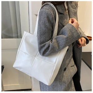 Close-up of white quilted tote bag with large square stitching and matte leather texture