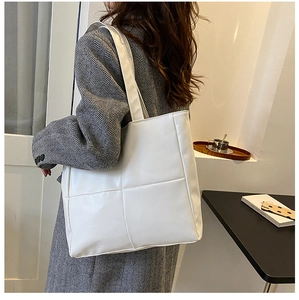 Close-up of white oversized tote bag with square quilted stitching on casual shoulder strap