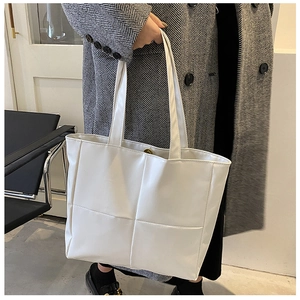 Detail of white large tote bag featuring modern cross-stitch faux leather design