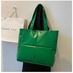 Close-up of a green faux leather tote bag featuring a quilted large square pattern design