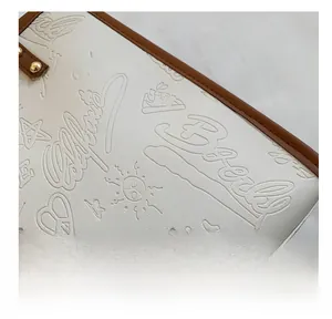 Detail of white lychee leather bag featuring premium stitching and embossed graffiti patterns
