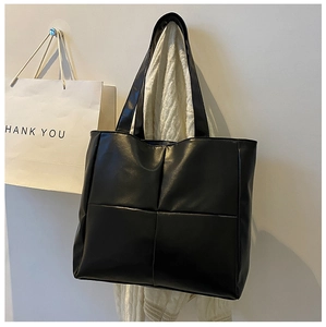 Detail view of large black tote bag with quilted square patterns in soft PU leather