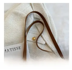 Detail view of cream tote bag with letter embossing and durable brown leather straps
