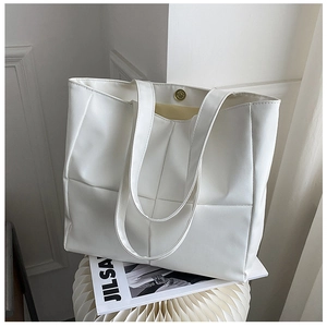 White quilted tote bag with large capacity featuring gold magnetic closure on white pedestal