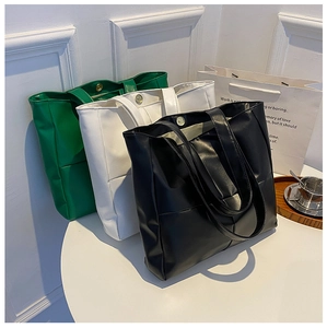 Detailed shot of large PU leather tote bags in green, white, and black with magnetic closure