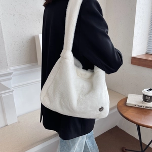 Minimalist white plush tote bag with wide strap worn by a model in casual black suit jacket