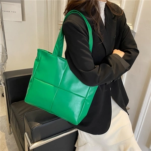 Vibrant green woven tote bag with large capacity, worn by model in minimalist indoor setting