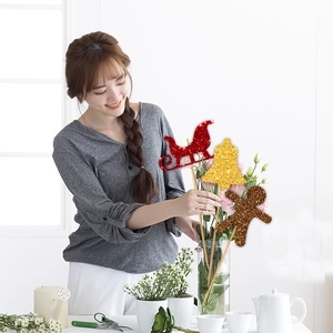 Close-up of glittery Christmas reindeer and gingerbread man picks being placed in a vase
