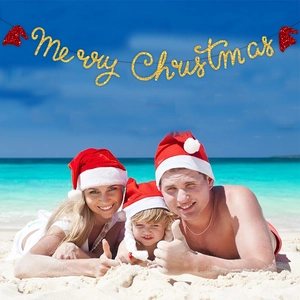 Bannière dorée Merry Christmas à paillettes avec bonnets de Noël sur fond de plage ensoleillée
