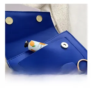 Detail of royal blue flap crossbody bag featuring gold hardware and front pocket