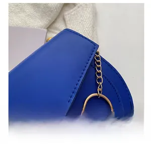 Detailed close-up showing fine stitching and gold chain hardware on a blue leather bag