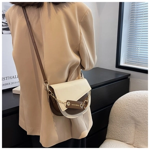Detail of a contrast color saddle bag with gold chain and fashion leather tag