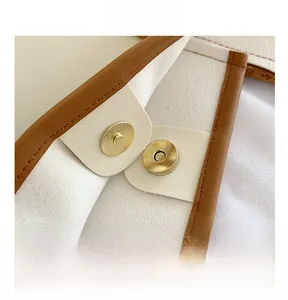 Detailed close-up of a high-quality gold magnetic buckle on a white leather handbag