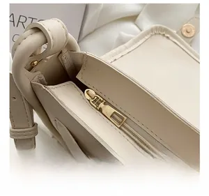 Detail of premium gold zipper hardware and smooth beige faux leather on stylish square bag