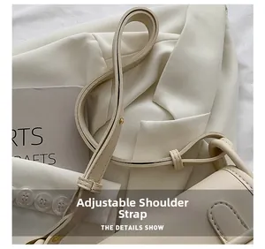 Detail view of the adjustable shoulder strap and gold buckle on a beige leather bag