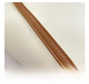 Close-up of precise stitching and leather texture on a stylish white and brown tote bag