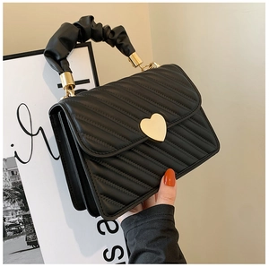 Detalle de bolso acolchado negro con cierre de corazón dorado y asa fruncida