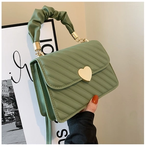 Detalle del bolso acolchado verde menta con cierre de corazón dorado y asa rizada