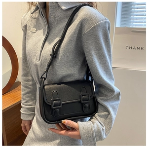 Classic black vintage crossbody bag with dual buckles and adjustable strap on a model