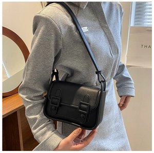Detailed side view of a vintage black mini square bag worn by a model in warm light