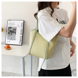 Close-up of a light green textured leather tote bag showing fine stitching and glossy finish